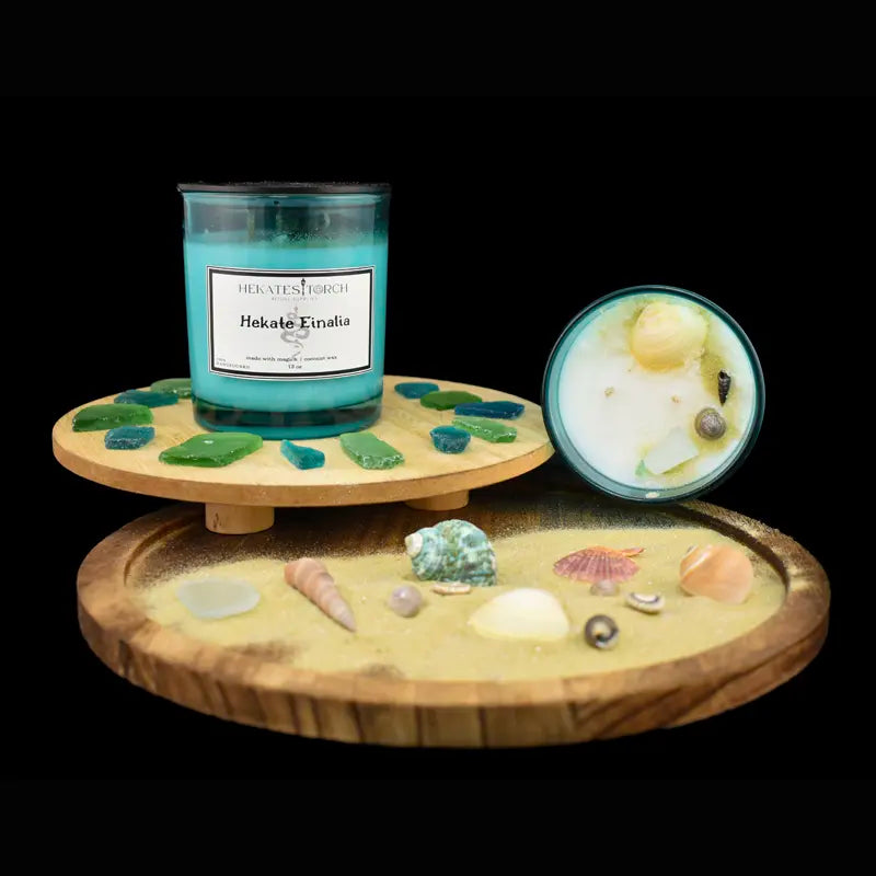 Candle with decorative stones and shells on a wooden stand against a black background