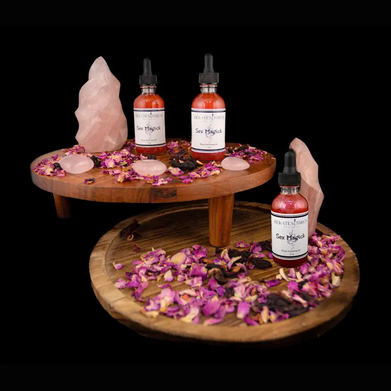 Sex Magick Ritual Oil Bottles with rose quartz and rose petals on a wooden tiered stand